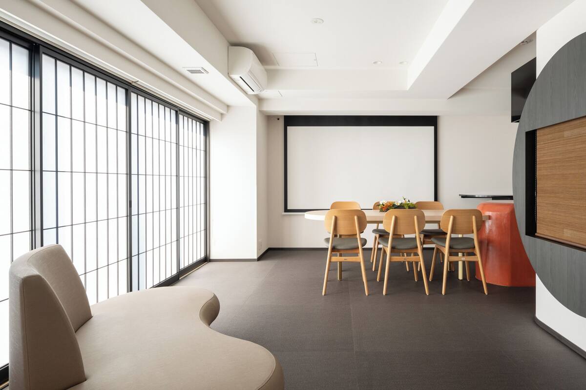 Una sala de conferencias moderna con una pantalla grande, una mesa redonda y varias sillas.