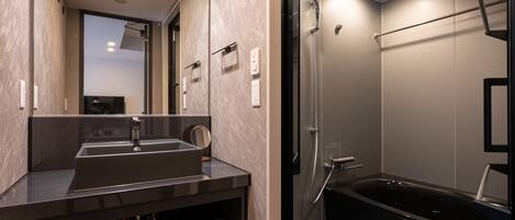 Un baño moderno con un espejo grande, un lavamanos y una bañera negra.