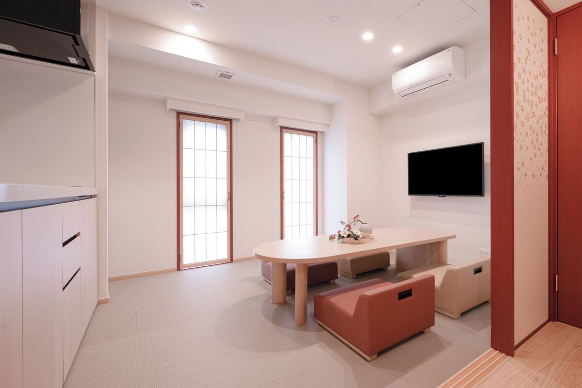 Habitación moderna y minimalista con una mesa de comedor, sillas, televisor y almacenamiento empotrado.