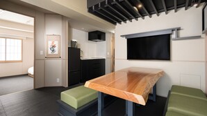 A compact kitchen with a built-in stove, a black refrigerator, and a wooden dining table with green cushioned benches. - MIMARU Osaka Shinsaibashi North (Osaka)