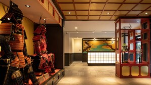 A traditional Japanese interior with a display of samurai armor, a reception desk with a floral mural, and a wooden ceiling. - MIMARU Osaka Shinsaibashi North (Osaka)
