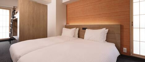 A large bed with a wooden headboard and two pillows, a wooden wardrobe, and a window with blinds.