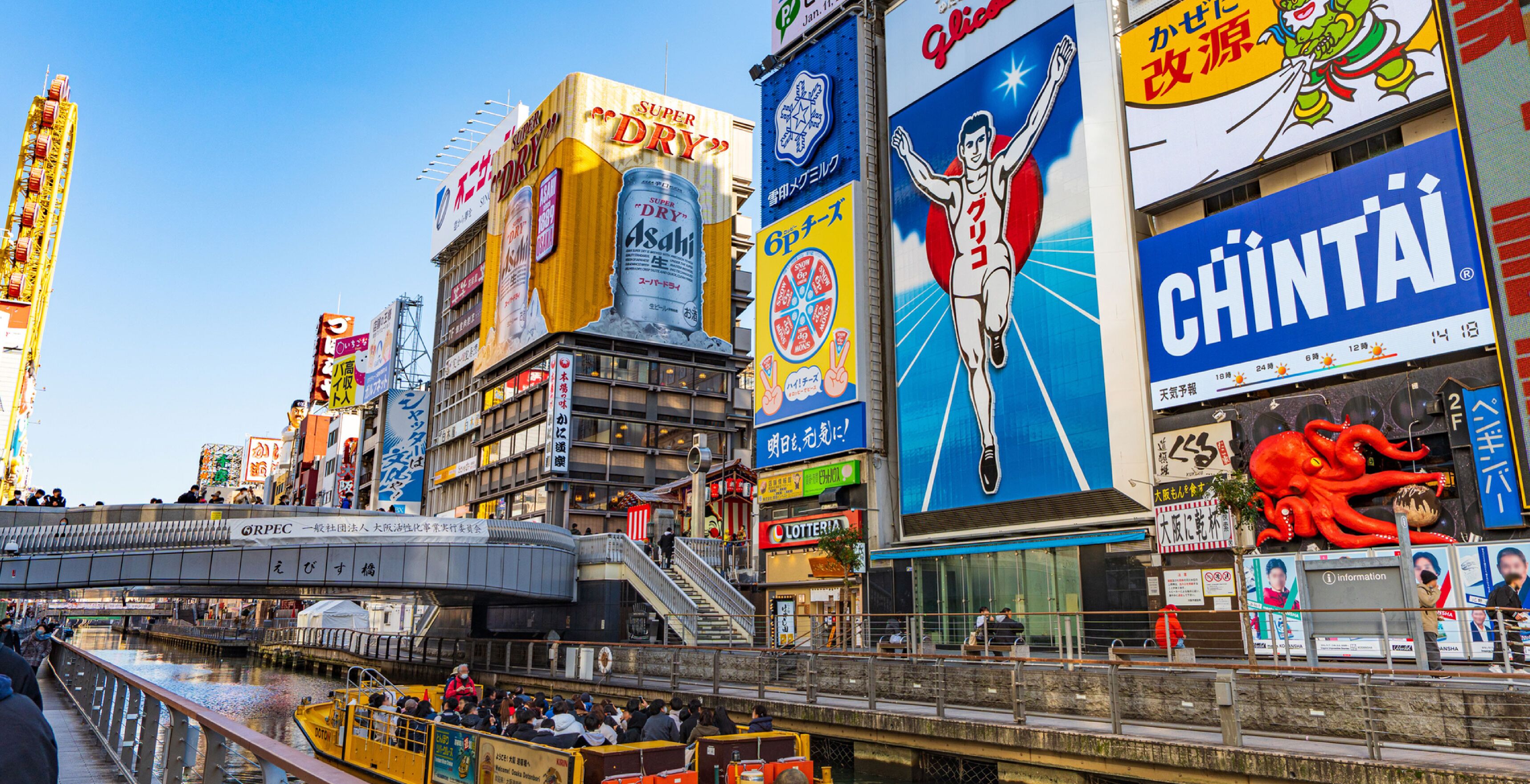 Una bulliciosa calle urbana con diversos edificios comerciales y vallas publicitarias.