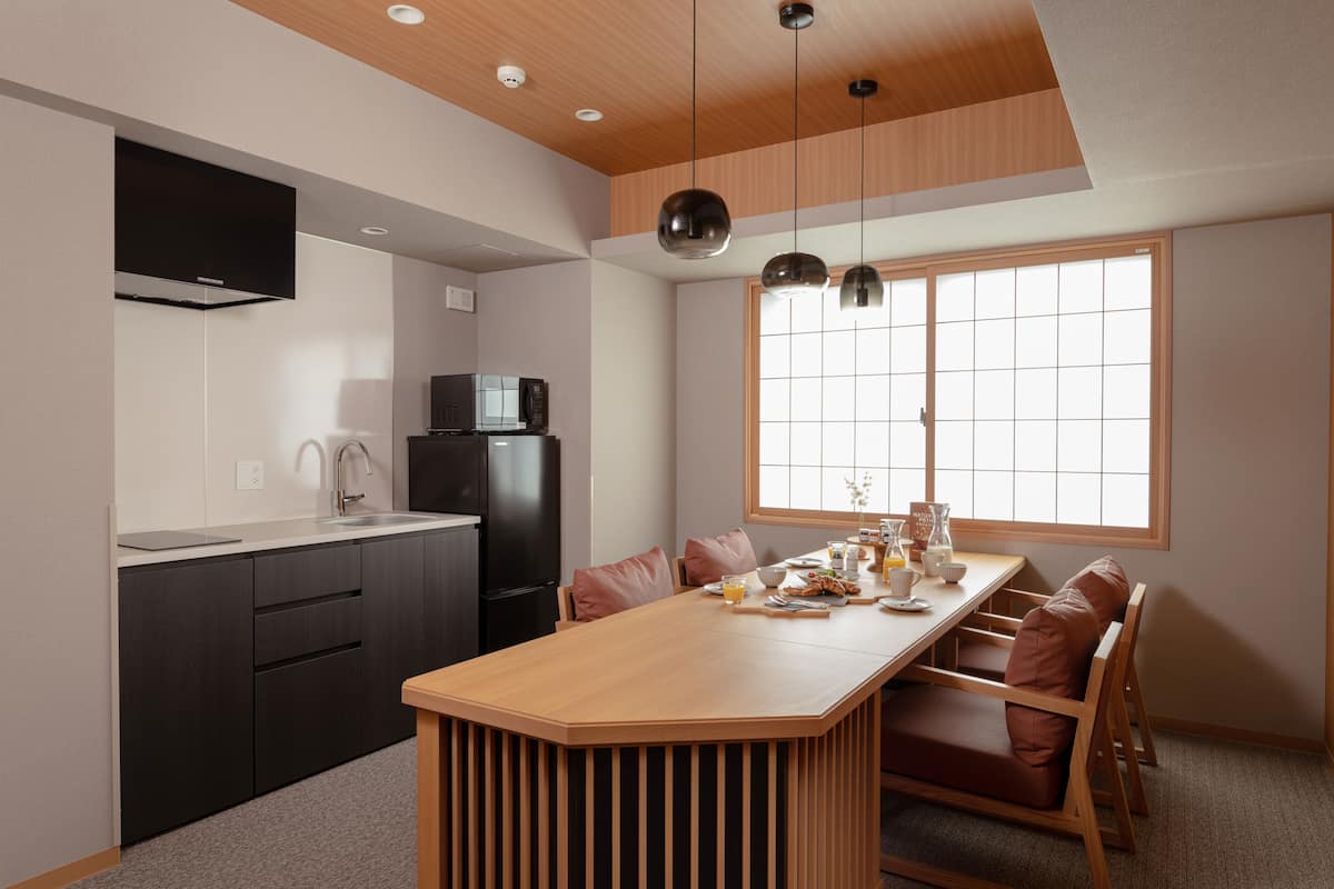 A modern kitchen with a central island, black appliances, and a large window providing natural light.