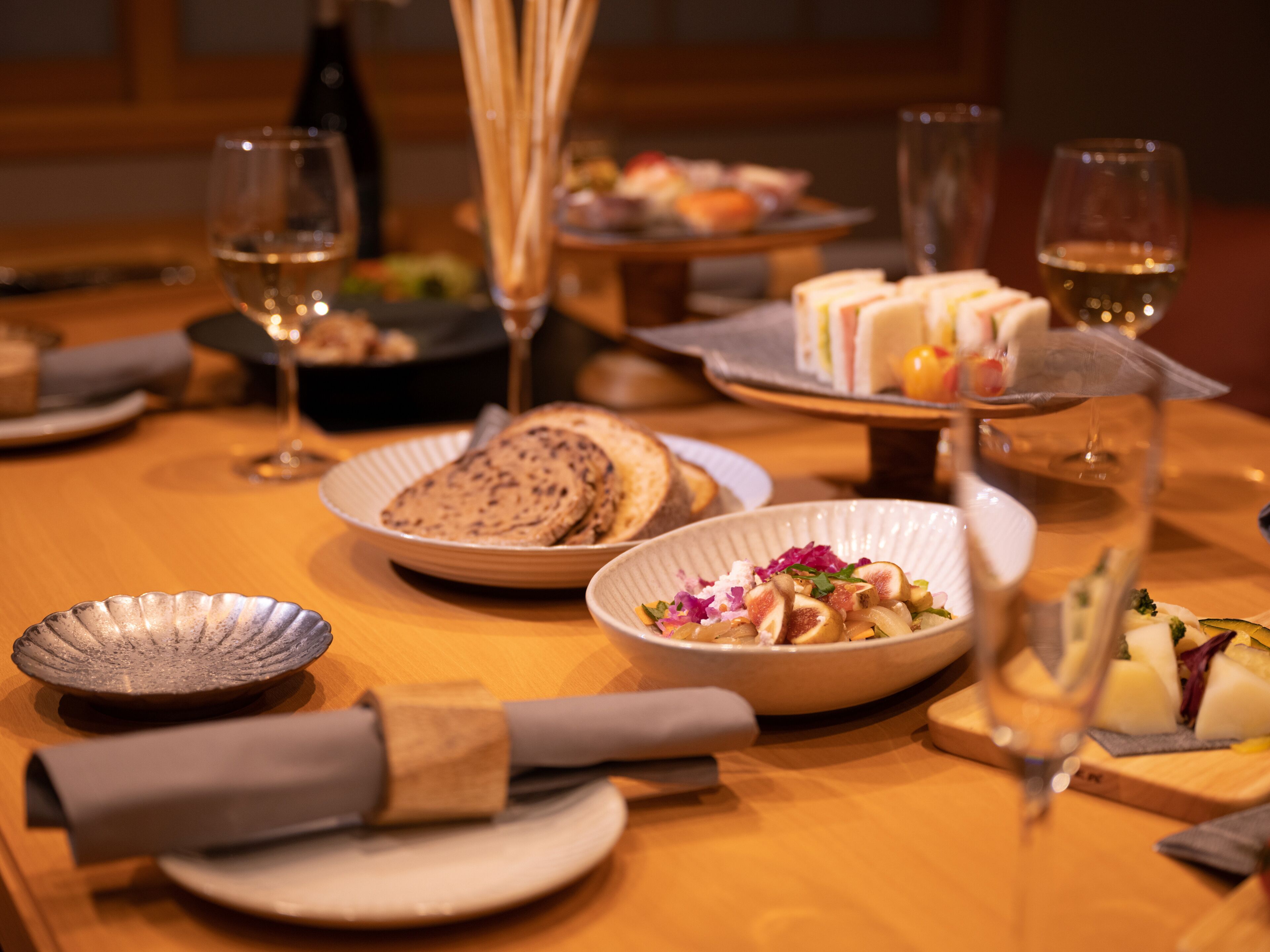 Une table à manger avec différents plats, des verres de vin et une bouteille.