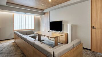 Un salon moderne avec un canapé d’angle, une table basse en bois, un téléviseur à écran plat et une porte coulissante.