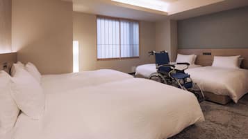 A hotel room with two beds, a wheelchair, and a large window.