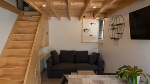A wooden staircase leading to a loft bedroom with a dark grey sofa and a small table.