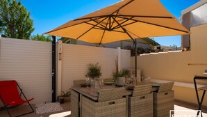 An outdoor patio area with a wicker bar, a red chair, and a yellow umbrella.