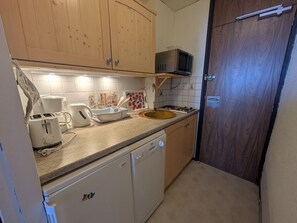 A compact kitchen with wooden cabinets, a microwave, a toaster, and a sink.