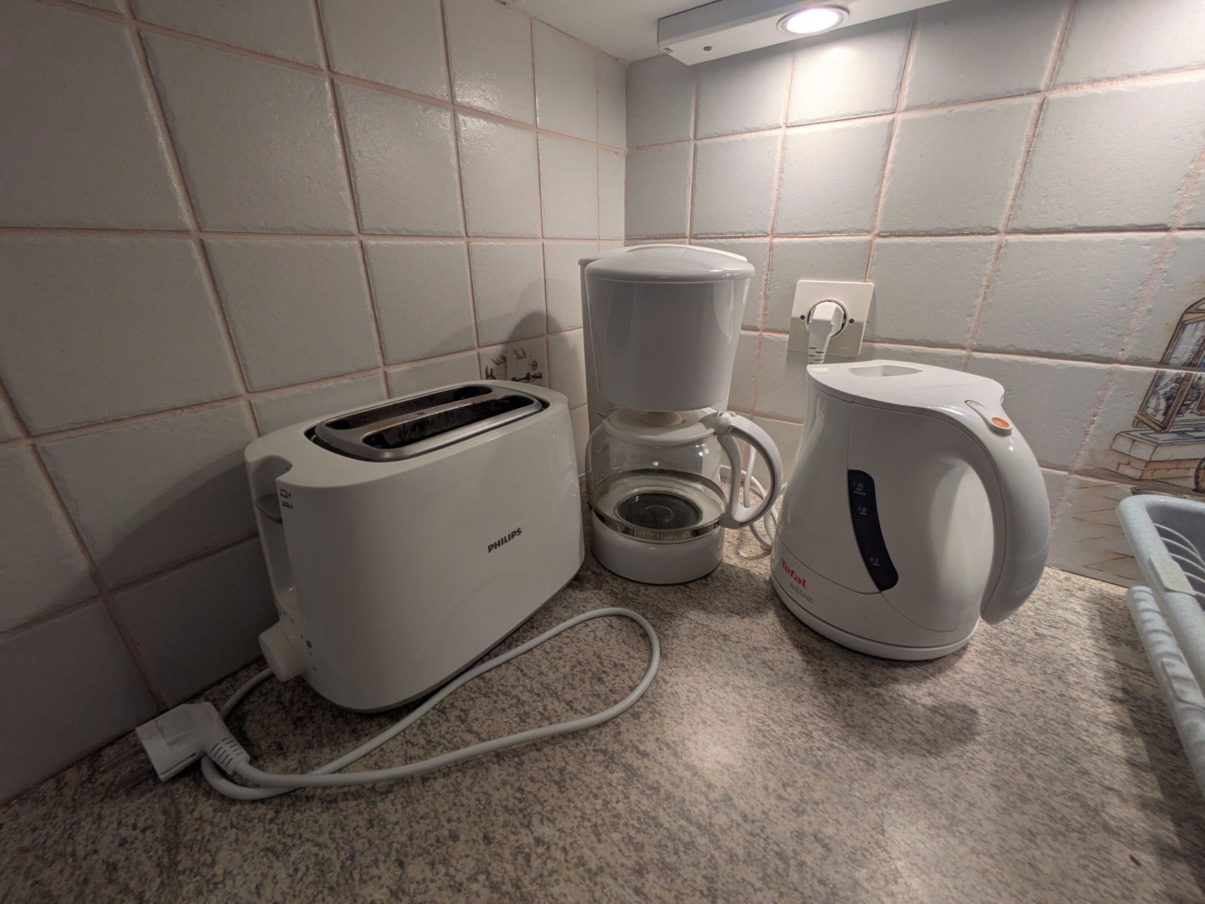 Une petite cuisine équipée d’un grille-pain Philips, d’une machine à café et d’une bouilloire, le tout posé sur un plan de travail en granit.