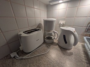 A kitchenette with a Philips toaster, a coffee maker, and a kettle on a granite countertop.