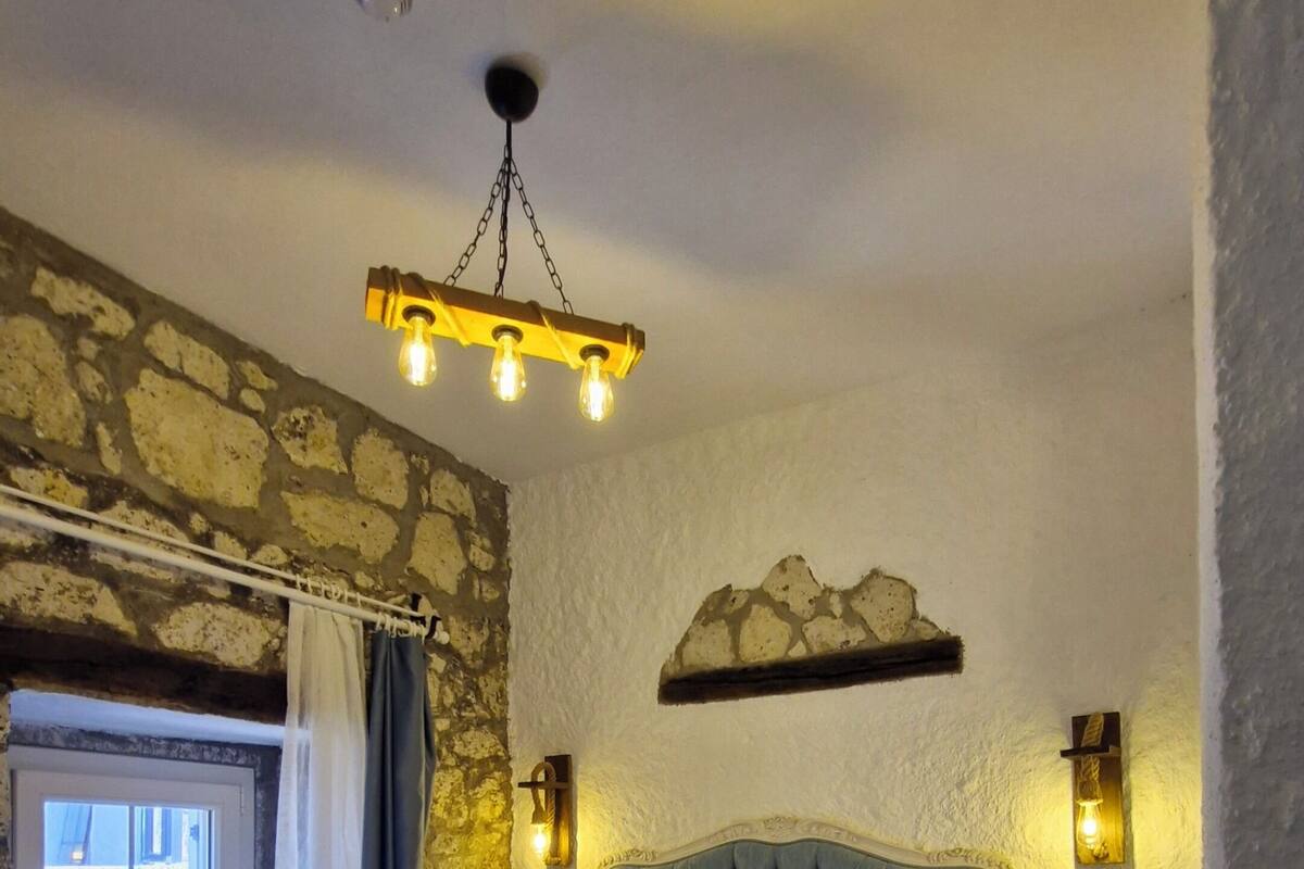Ein Schlafzimmer mit Bett, Nachttisch, Wandlampe und Steinwand.