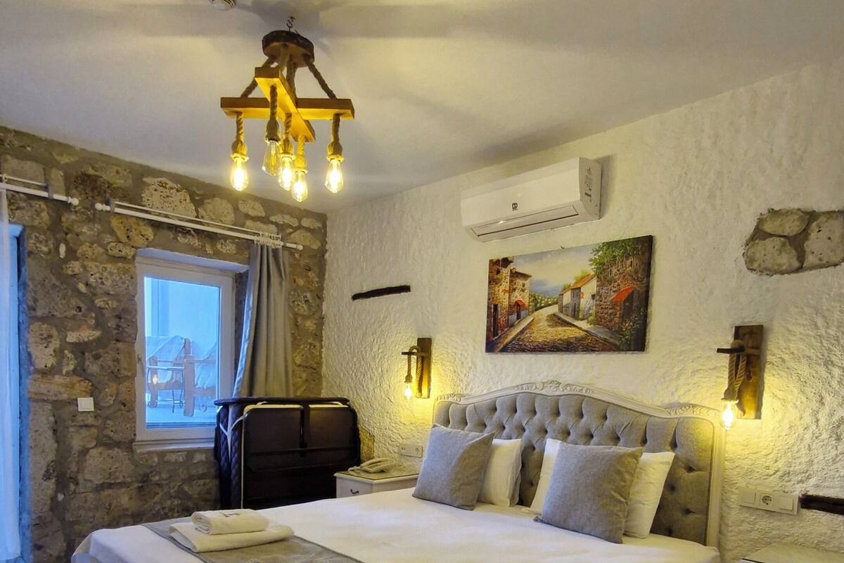 Ein Schlafzimmer mit einem großen Bett, einer Steinwand, einem Fenster und einem Gemälde.