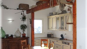 Une cuisine rustique avec des poutres en bois, une table à manger avec des chaises et une fenêtre laissant entrer la lumière naturelle.