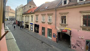 A cobblestone street lined with historic buildings, some with commercial establishments. - Cilindar Apartments (Zagreb)