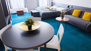A modern hotel room with a bed, a sofa, a round table with a plant, and a small side table. - Cilindar Apartments (Zagreb)