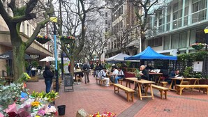Un café en plein air avec des tables et des bancs en bois, entouré d’une variété de fleurs et de plantes.