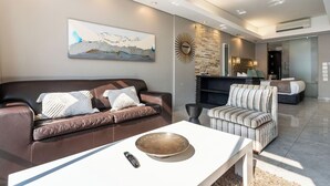 Un salon moderne avec un canapé en cuir marron, une table basse blanche et un fauteuil à rayures.