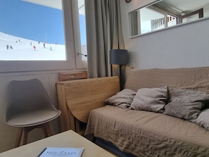 Hotelkamer met een bed, een stoel, een tafel en een raam met uitzicht op een besneeuwd landschap.