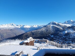 Un paysage montagneux enneigé avec une station de ski, comprenant des bâtiments et des remontées mécaniques.