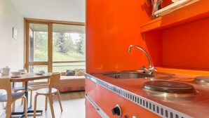 A compact kitchen with a sink, stove, and wooden dining area with chairs and a table.