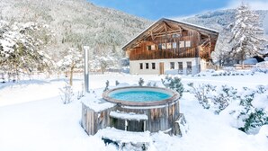 A wooden chalet with a hot tub in a snowy landscape. - Detached 500m2 Farmhouse with Yoga Studio, Hot Tub and Sauna (Samoëns)