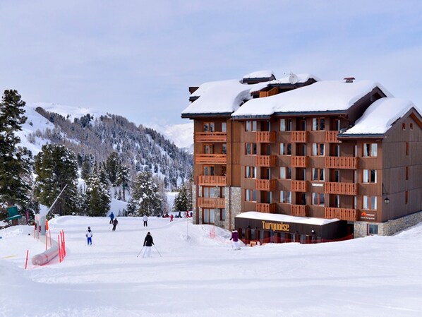 A multi-story hotel with a ski slope in the background.