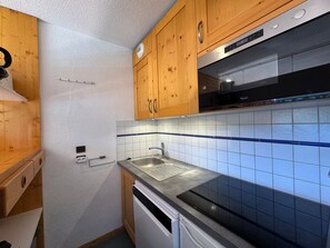 A kitchen with wooden cabinets, a stainless steel sink, and a dishwasher.