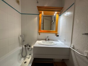 A bathroom with a white sink, a mirror, and a shower.