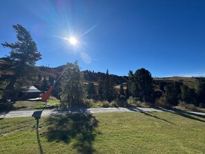 A clear sky with a bright sun, a grassy area, and a mountain in the background.
