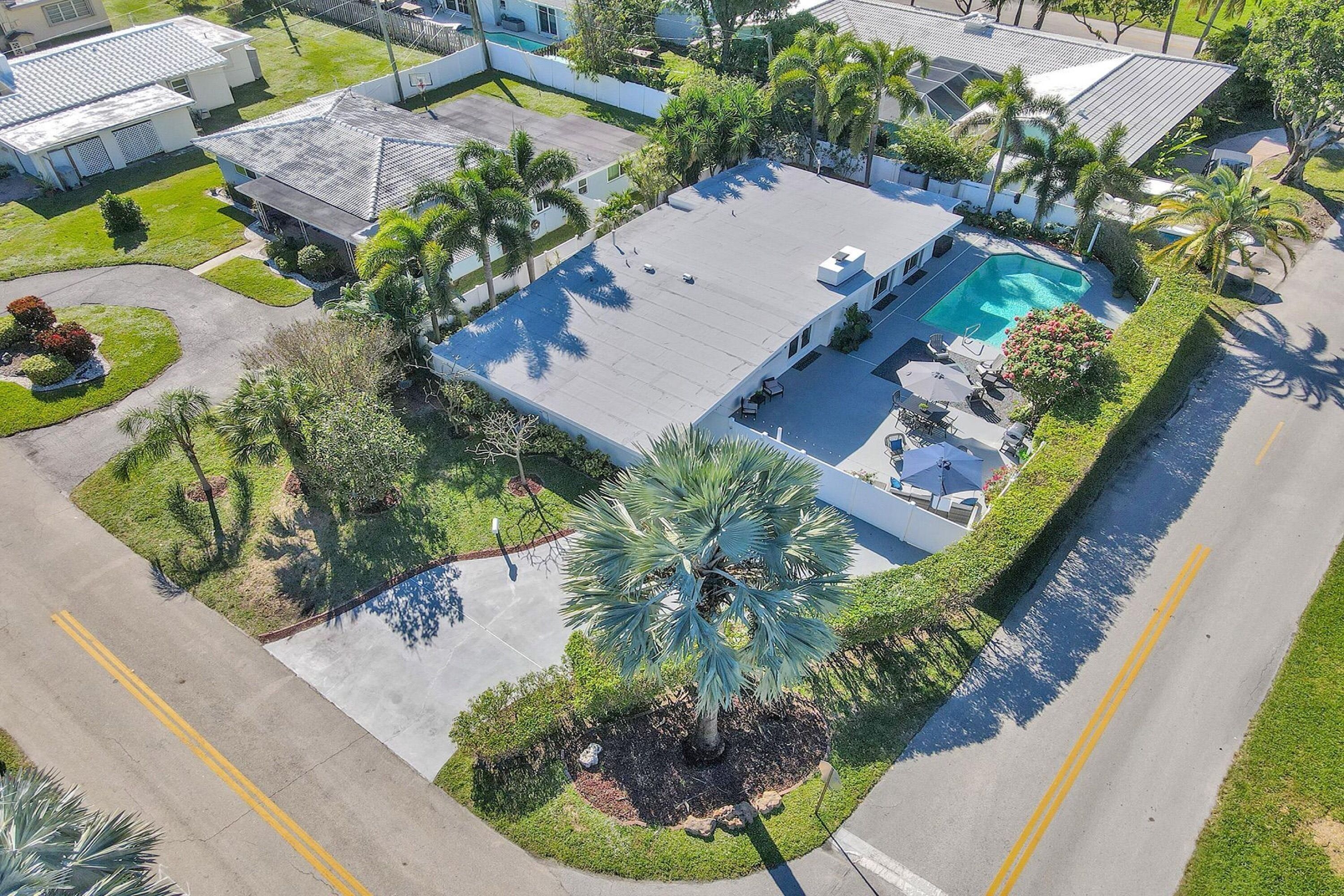 An aerial view of a residential property with a swimming pool, multiple buildings, and well-maintained landscaping.
