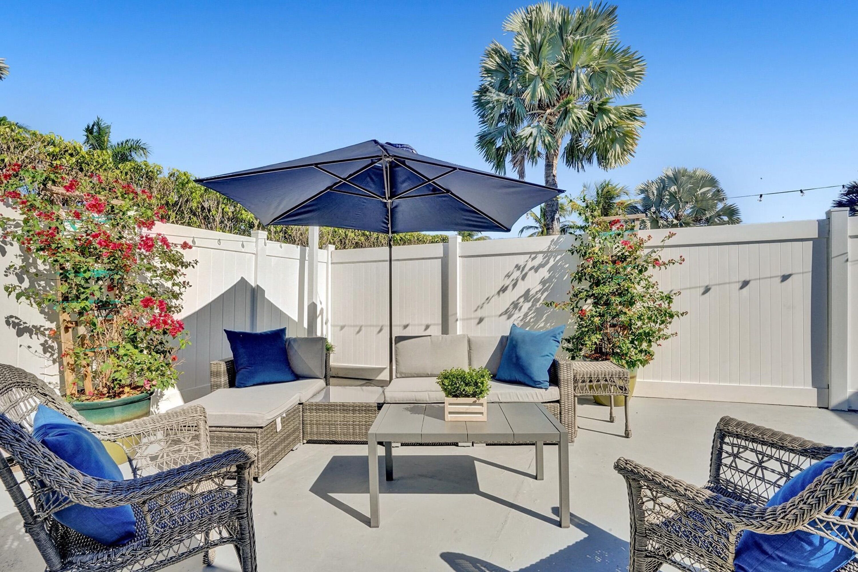 An outdoor patio with wicker furniture, a table, and a large umbrella.