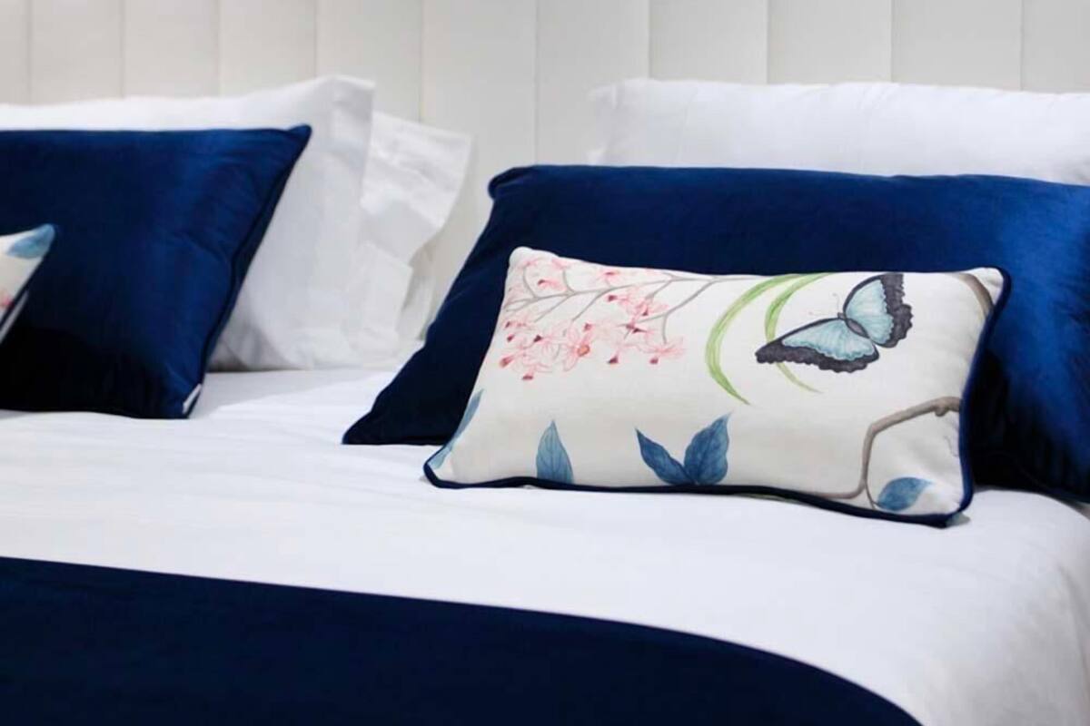 Un lit bien fait, avec du linge de lit blanc et des oreillers bleus.