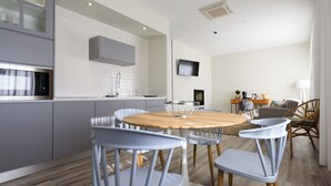 A modern kitchen with grey cabinets, a stainless steel oven, and a wooden dining table with four chairs. - Hotel Campo do Rosmaninho (Castelo Branco)