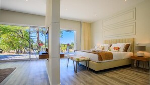 A modern bedroom with a large bed, a bedside table, and a view of the outdoors through a sliding door. - Hotel Campo do Rosmaninho (Castelo Branco)