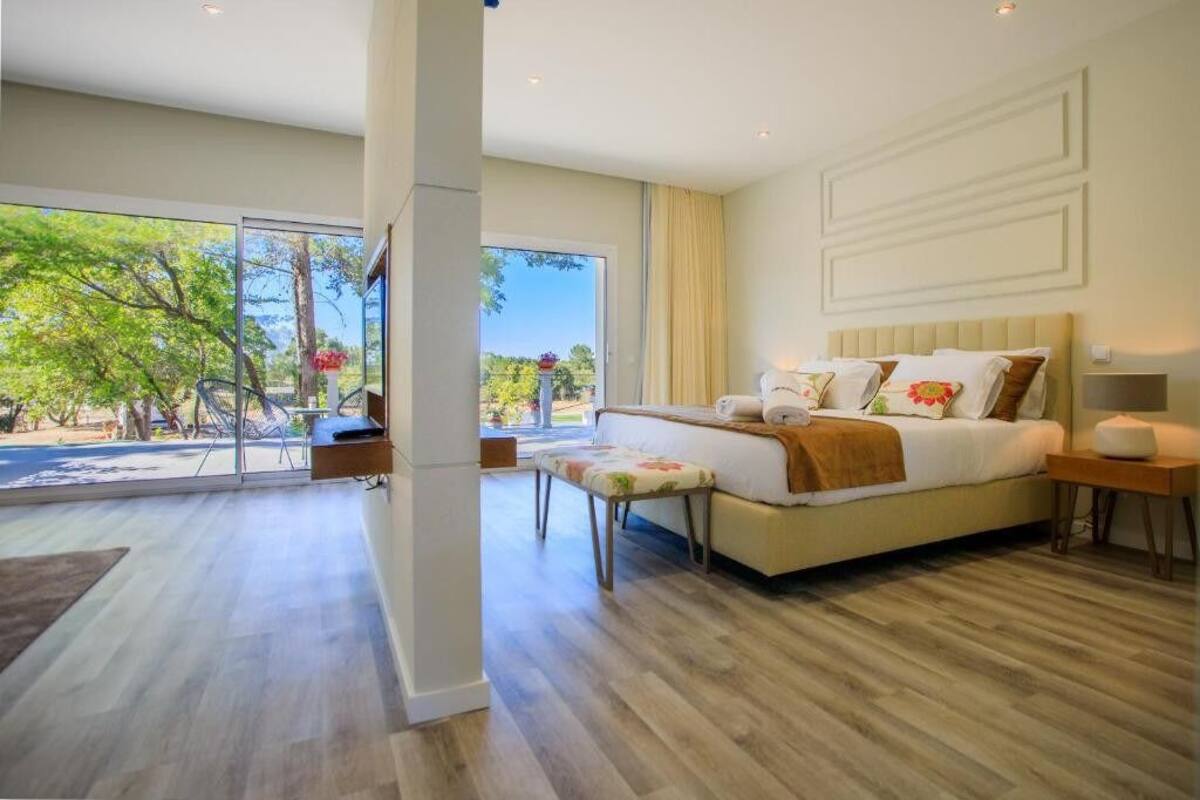 Une chambre à coucher moderne, dotée d’un grand lit, d’une table de chevet et offrant une vue sur l’extérieur grâce à une porte coulissante.
