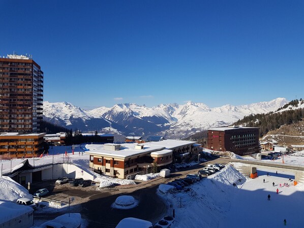 Un hôtel au design moderne, situé dans une région montagneuse enneigée, offrant une vue dégagée sur les sommets environnants.