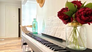 A piano with sheet music, a vase with red flowers, and a hat on the wall. - Renovated T3 Apt with Balcony & Parking in Annecy Center (Annecy)