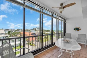 A balcony with a view of a residential area, a ceiling fan, and a table with chairs.
