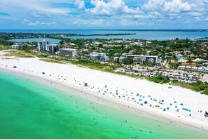 A coastal resort with a beachfront, multiple buildings, and a clear view of the ocean.