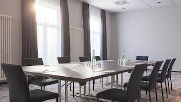 Una sala conferenze con un lungo tavolo, sedie e una bottiglia d'acqua.
