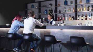A bar area with stools, a counter, and shelves with bottles.