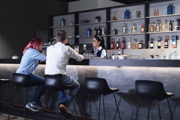 Un espace bar avec des tabourets, un comptoir et des étagères remplies de bouteilles.