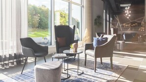 A modern lounge area with large windows, comfortable seating, and a view of the outdoors. - Candlewood Suites Augsburg by IHG (Gersthofen)