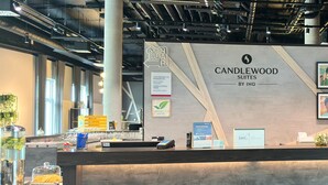 A reception desk with a sign for Candlewood Suites by IHG, a glass display case with snacks, and a digital payment terminal. - Candlewood Suites Augsburg by IHG (Gersthofen)