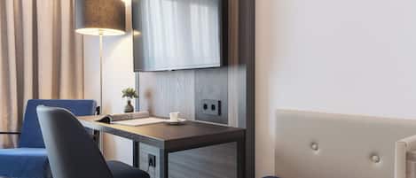 Una habitación de hotel moderna con escritorio, silla, televisor y cama.