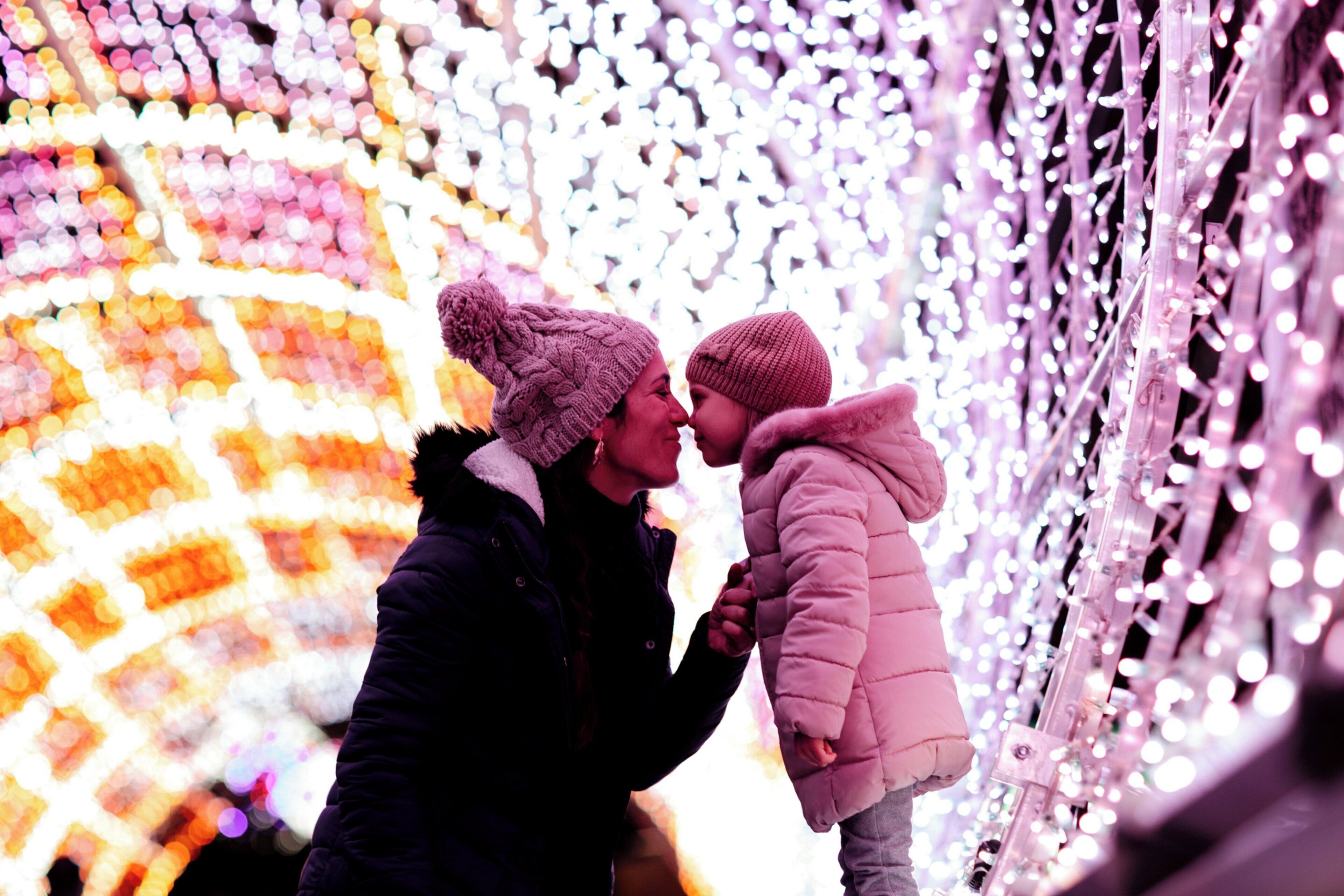 Una pareja tomándose de las manos frente a una instalación de luces decorativas.