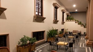A spacious indoor area with multiple seating arrangements, including chairs and sofas, and a staircase with potted plants. - Hanuwant Niwas (Jodhpur)