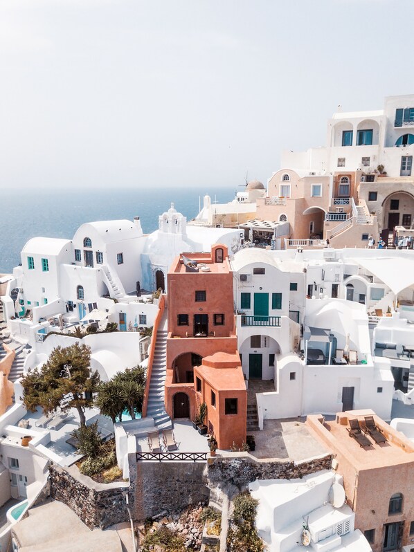 A coastal town with white buildings, a prominent red-roofed structure, and a clear view of the sea.